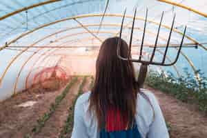 Free photo back view of a young female with a grass raking tool