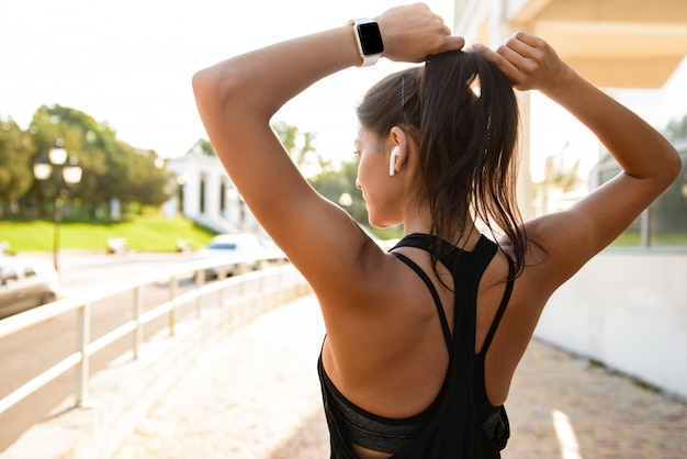 Back view of a young fitness woman in earphones