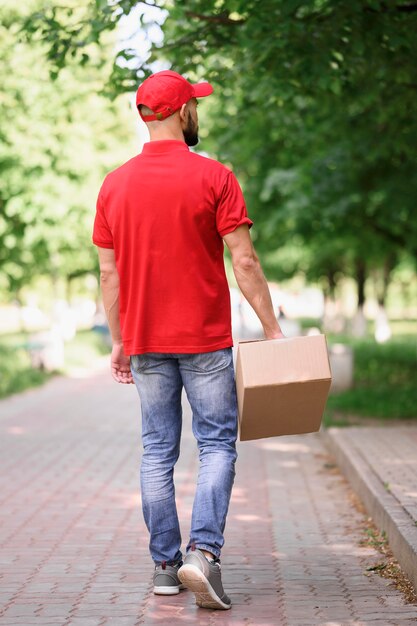 Back view young man delivering cardboard box