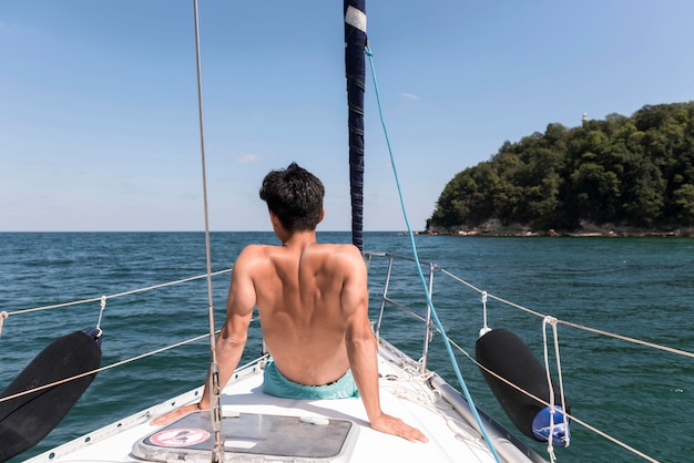 Free Photo back view young man enjoying vacation on boat