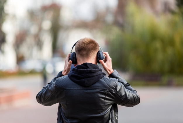 Back view young man listening to music on headphones