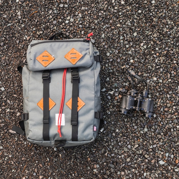 Free photo backpack and binoculars on gravel