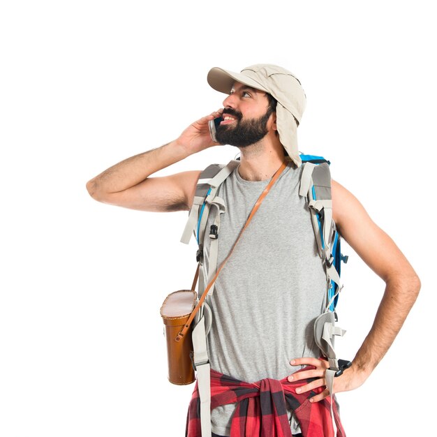 Backpacker talking to mobile over white background