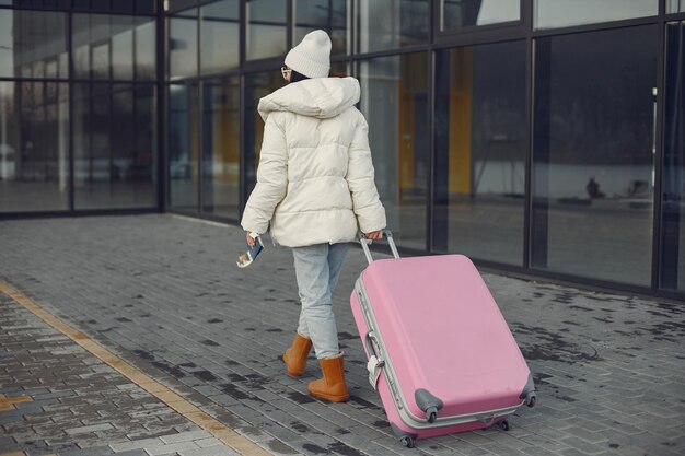 Backside photo of woman with luggage going to airport terminal