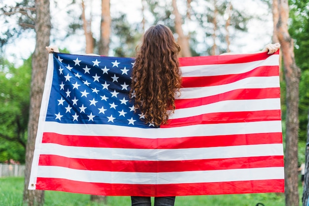 Free photo backview of girl with american flag in nature