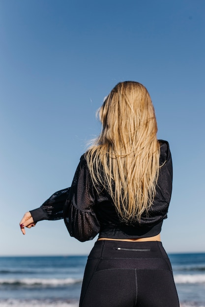 Backview woman stretching at the beach