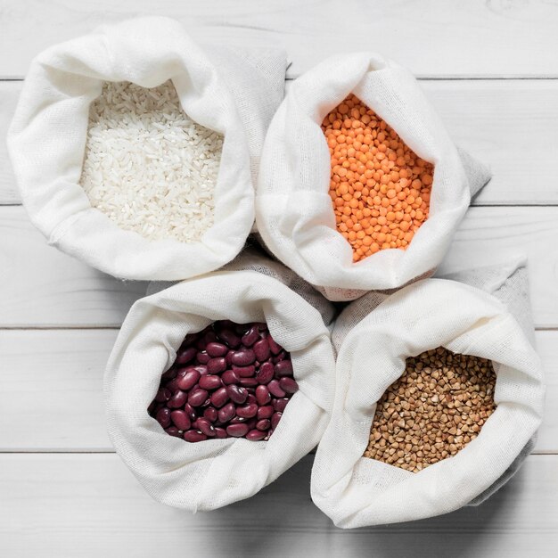 Bags with different beans on wooden background