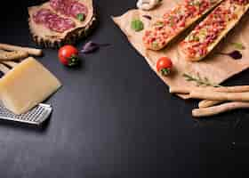 Free photo baguette pizza with italian food ingredients over black stone surface