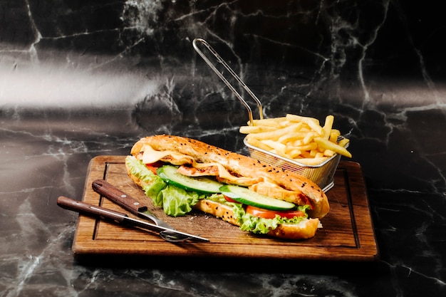 Free Photo baguette sandwich with mixed ingredients and french fries on a wooden board.