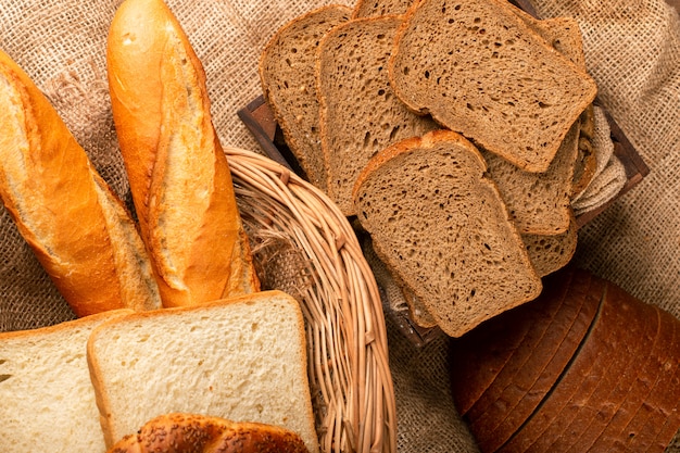 Baguette with slices of brown and white bread in basket