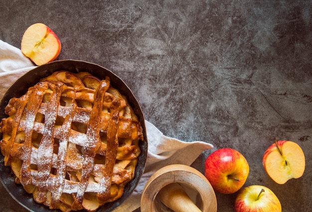 Baked apple pie on wooden table with fruit