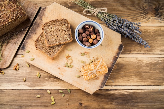 Baked bread and energy bar on chopping board over the table