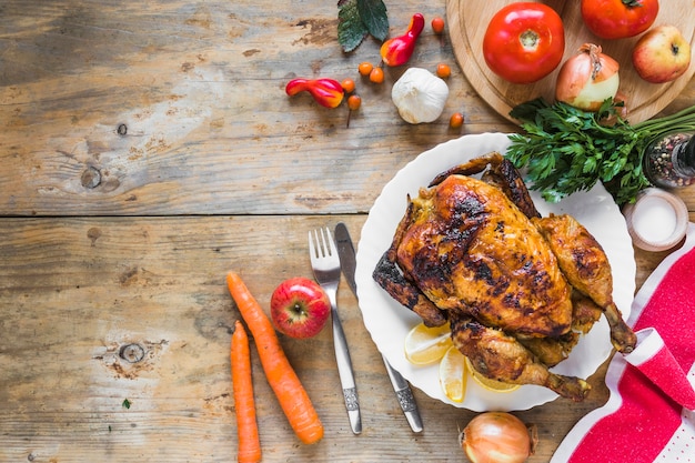 Free photo baked chicken between different vegetables, spoon and knife