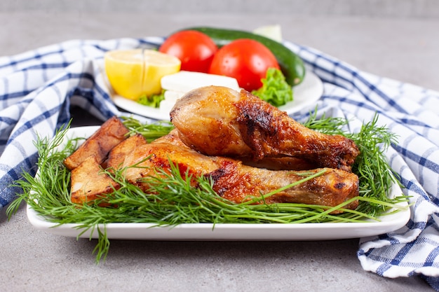 Free photo baked chicken legs with greens on a white plate