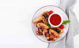 Free photo baked chicken wings in the asian style and tomatoes sauce on plate