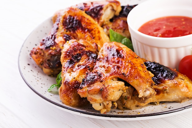 Baked chicken wings in the Asian style and tomatoes sauce on plate.