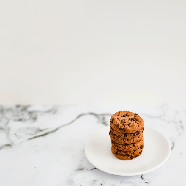 Baked cookies stack on white plate over the marble backdrop