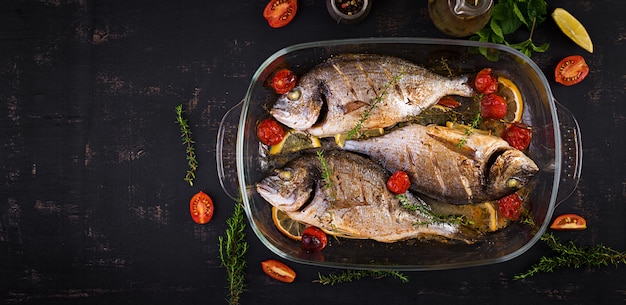 Baked fish dorado with lemon and herbs in baking pan