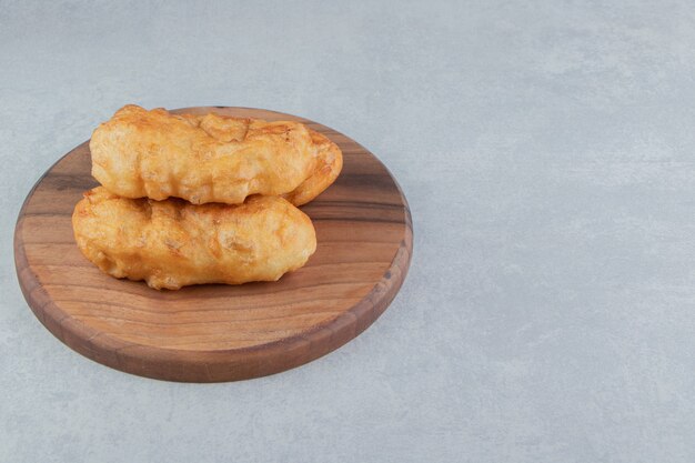 Baked piroshki with potatoes on wooden board. 