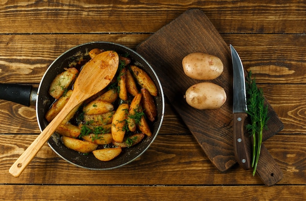 Baked potatoes in a frying pan with raw potatoes and dill