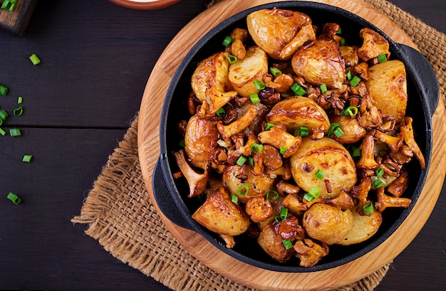 Free photo baked potatoes with garlic, herbs and fried chanterelles in a cast iron skillet. top view