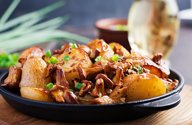 Free photo baked potatoes with garlic, herbs and fried chanterelles in a cast iron skillet.