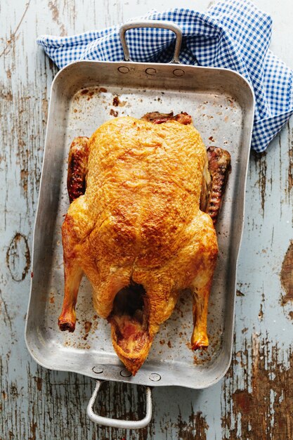 Baked roasted duck with vegetables on pan on old wooden background. Top View.