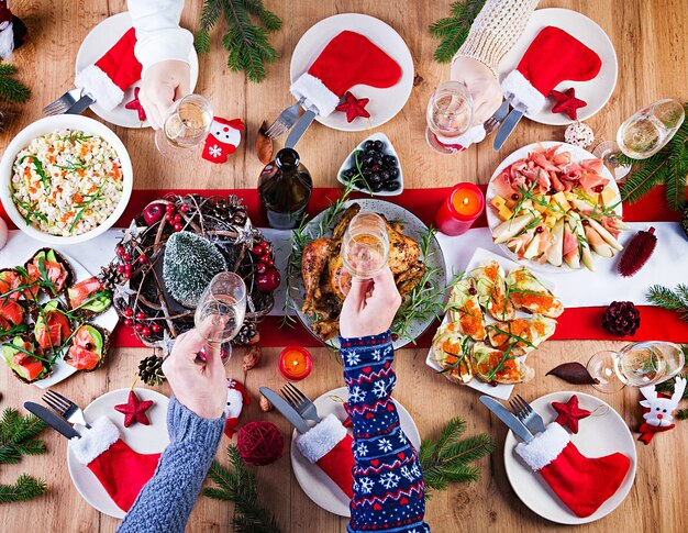 Baked turkey. Christmas dinner. The Christmas table is served with a turkey, decorated with bright tinsel and candles. Fried chicken, table.  Family dinner. Top view, hands in the frame