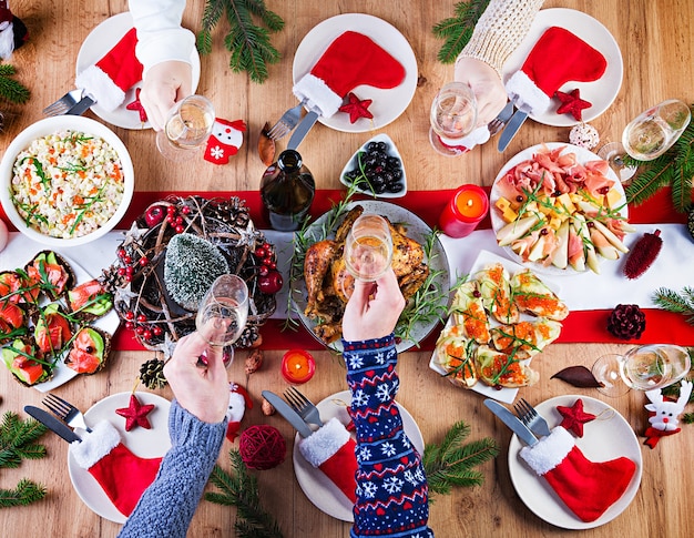 Baked turkey. Christmas dinner. The Christmas table is served with a turkey, decorated with bright tinsel and candles. Fried chicken, table.  Family dinner. Top view, hands in the frame