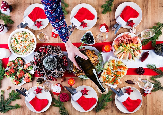 Free photo baked turkey. christmas dinner. the christmas table is served with a turkey, decorated with bright tinsel and candles. fried chicken, table.  family dinner. top view, hands in the frame