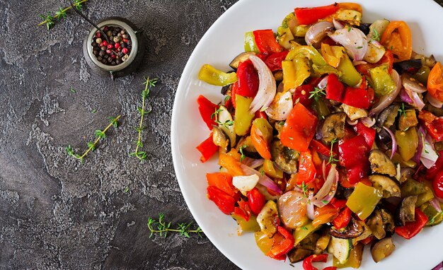 Baked vegetables on white plate. Eggplant, zucchini, tomatoes, paprika and onions. Top view