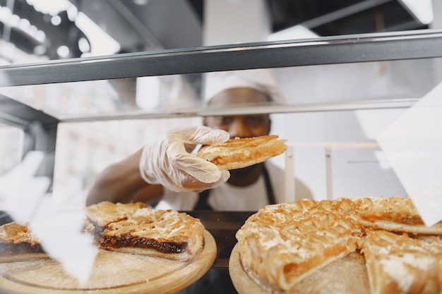 Free Photo baker arranging showcase in bakery. selling product to a customer.