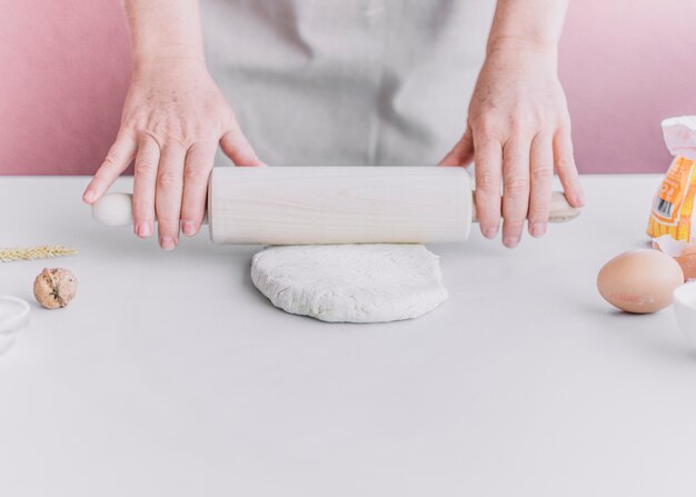 Baker flattening dough with rolling pin