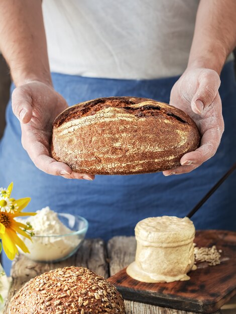 The baker holds homemade craft bread in his hands