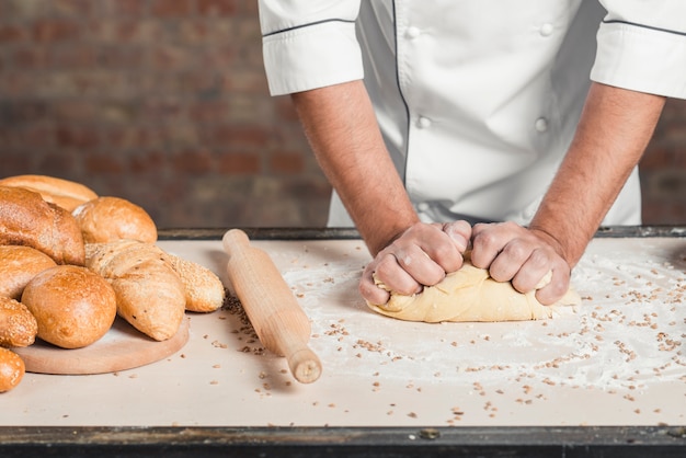 Free photo baker kneading the dough on counter