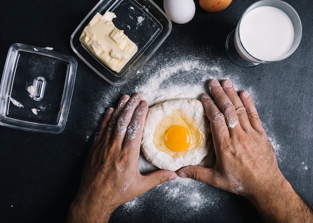 Free Photo baker kneading dough with egg york on kitchen counter