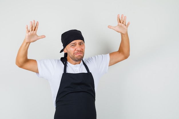 Baker man raising hands in helpless gesture in t-shirt