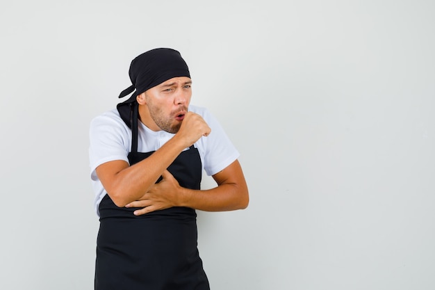 Baker man suffering from cough in t-shirt, apron and looking sick.