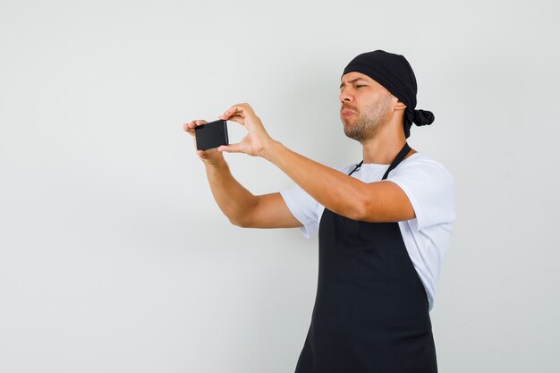 Baker man taking photo on mobile phone in t-shirt