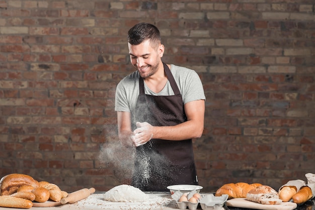 Free Photo baker's hand clapping a flour with ingredients on counter