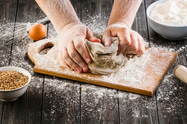 Free photo baker's hand kneading dough with flour on chopping board