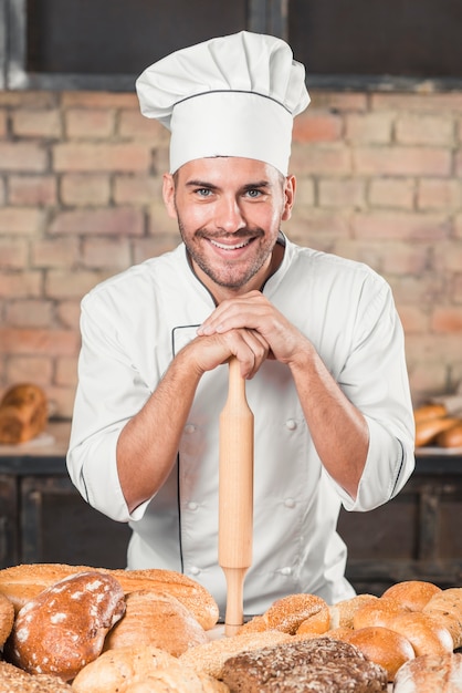 Baker standing behind the table with variety of baked breads