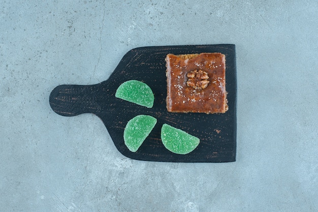 Bakhlava and jelly candies on a black board on marble surface