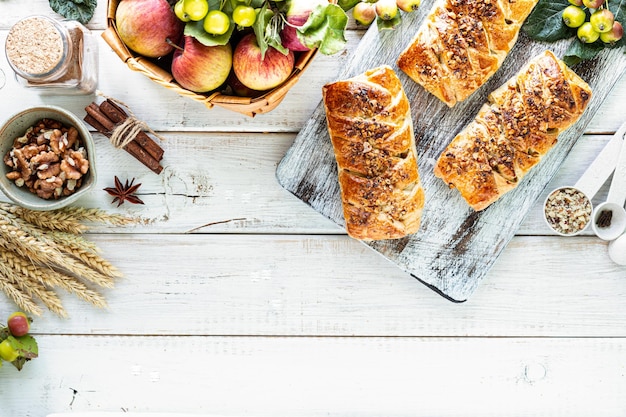 Free photo baking with apple freshly baked apple and cinnamon rolls made from puff pastry on a white wooden table top view rustic style copy space