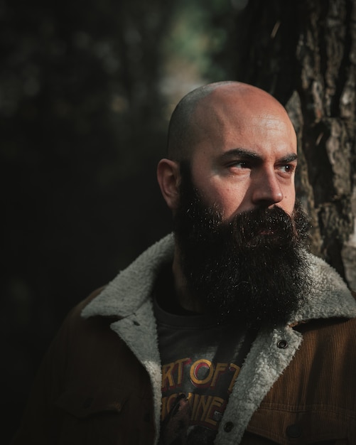 Bald headed man with a dense black mustache in the park looking towards the sun