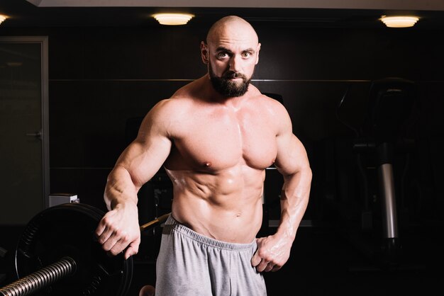 Bald man posing near barbell