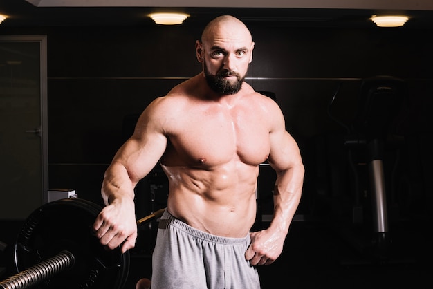 Bald man posing near barbell