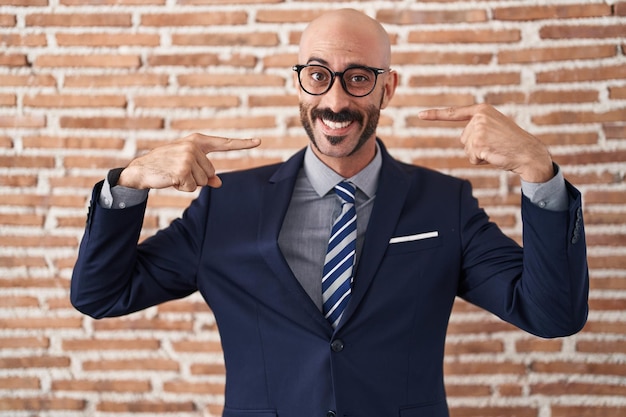 Free photo bald man with beard wearing business clothes and glasses smiling cheerful showing and pointing with fingers teeth and mouth dental health concept