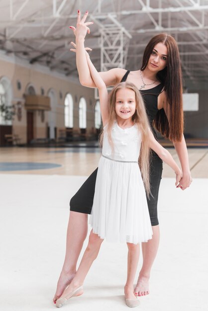 Ballerina instructor with her student posing in dance class