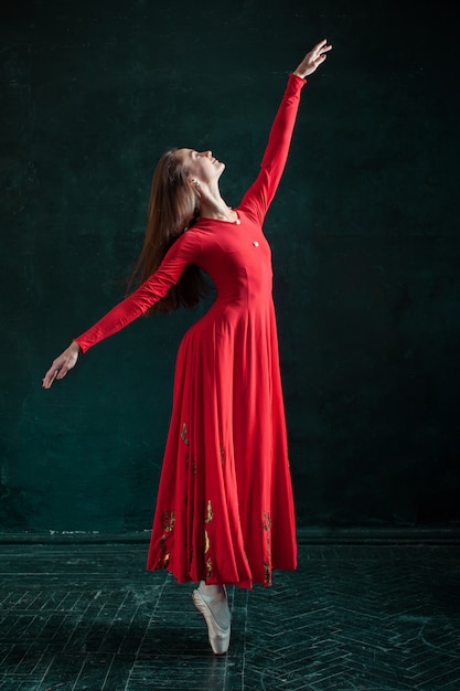 Ballerina posing in pointe shoes at black wooden pavilion